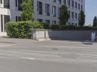 man riding a bike down the street in front of a large building with a red sign