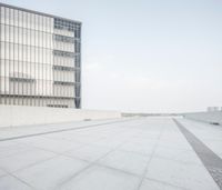 an empty parking lot next to a tall building in the city that has windows on it