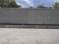 the building is concrete, which looks like the cement wall has a long line of trees