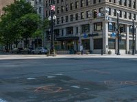 the green paint is painted on a bike path in front of an office building and large, trees