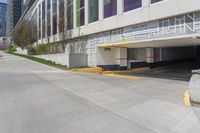 a parking area that has several parking spaces on the building side of it near trees, and a sidewalk