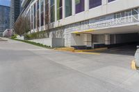 a parking area that has several parking spaces on the building side of it near trees, and a sidewalk