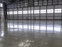 a warehouse with a shiny polished floor and concrete floors and red pipe spigong equipment