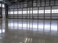 a warehouse with a shiny polished floor and concrete floors and red pipe spigong equipment