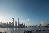 an asian city across the water on a beautiful day with sun shining and clouds above it