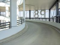 a curved walkway leads to a car park inside of the airport terminal building as well