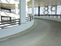 a curved walkway leads to a car park inside of the airport terminal building as well