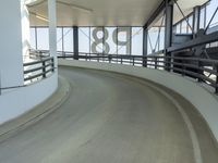 a curved walkway leads to a car park inside of the airport terminal building as well