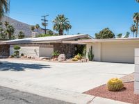 a house with desert landscaping in the front and a cacti plant and rock on the sidewalk