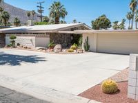 a house with desert landscaping in the front and a cacti plant and rock on the sidewalk