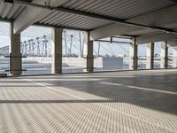 an empty parking garage on the water with some windows open and some cars parked near it