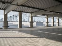 an empty parking garage on the water with some windows open and some cars parked near it