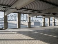 an empty parking garage on the water with some windows open and some cars parked near it