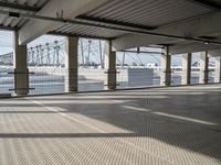 an empty parking garage on the water with some windows open and some cars parked near it