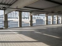 an empty parking garage on the water with some windows open and some cars parked near it