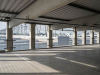 an empty parking garage on the water with some windows open and some cars parked near it