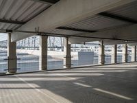 an empty parking garage on the water with some windows open and some cars parked near it