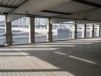 an empty parking garage on the water with some windows open and some cars parked near it