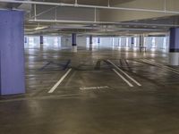 the empty parking lot of an underground building is painted purple and has blue numbers on the floor