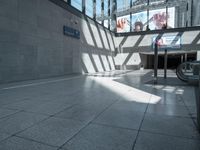 an empty hallway with light coming through it, with the ground next to it and two escalators on either side of the entrance