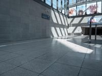 an empty hallway with light coming through it, with the ground next to it and two escalators on either side of the entrance