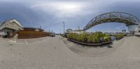 fisheye lens photo of a bridge and a marina with water on one side, houses at the other