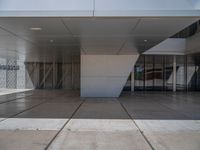 a white building with several steps and large glass panels in the facade is a mosaic that depicts a man