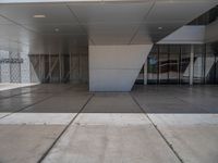 a white building with several steps and large glass panels in the facade is a mosaic that depicts a man