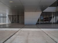 a white building with several steps and large glass panels in the facade is a mosaic that depicts a man