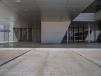 a white building with several steps and large glass panels in the facade is a mosaic that depicts a man