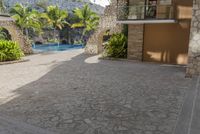 a courtyard near a pool with rocks and trees around it and palm trees in the distance