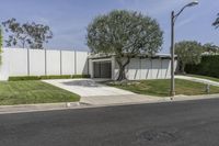 a concrete wall and a fence with trees in front of it along the street from an office building
