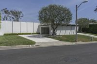 a concrete wall and a fence with trees in front of it along the street from an office building