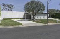a concrete wall and a fence with trees in front of it along the street from an office building