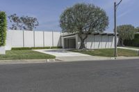 a concrete wall and a fence with trees in front of it along the street from an office building