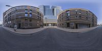 a wide angle view of two circular buildings with curved driveways and parking lots near the street