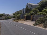 a street has several buildings with blue sky in the background and shrubs along both sides of the road