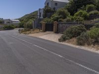 a street has several buildings with blue sky in the background and shrubs along both sides of the road