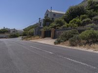 a street has several buildings with blue sky in the background and shrubs along both sides of the road