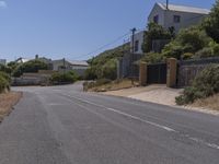 a street has several buildings with blue sky in the background and shrubs along both sides of the road