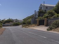 a street has several buildings with blue sky in the background and shrubs along both sides of the road