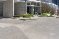 the empty parking lot near the building is empty of people or cars while in the front is a red fire hydrant and several trees