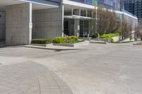 the empty parking lot near the building is empty of people or cars while in the front is a red fire hydrant and several trees