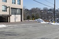 a parking garage on the side of a road in front of a building with lots of snow