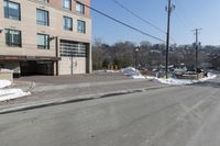 a parking garage on the side of a road in front of a building with lots of snow