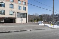 a parking garage on the side of a road in front of a building with lots of snow