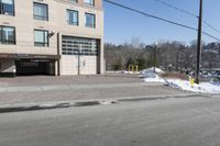 a parking garage on the side of a road in front of a building with lots of snow