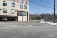 a parking garage on the side of a road in front of a building with lots of snow