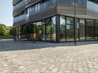 an outside view of a building with lots of glass walls and a stone pathway lined up