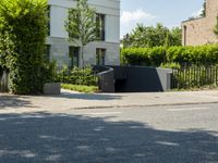 an empty street with an intersection of some trees and bushes in the foreground,